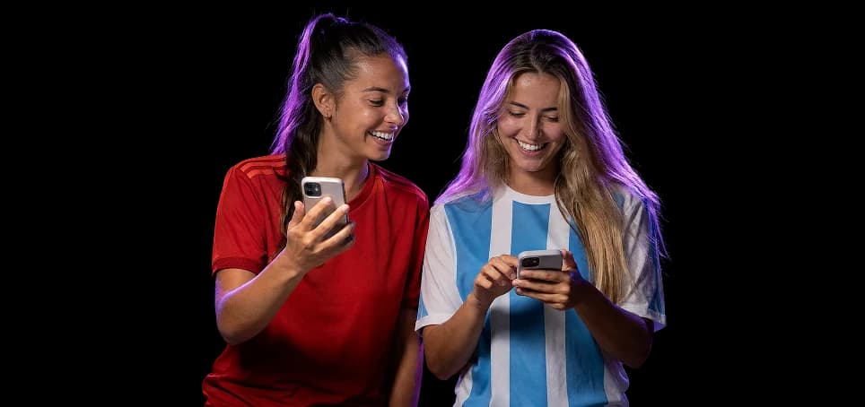 Two football fans in national-team jerseys shopping together on their phones